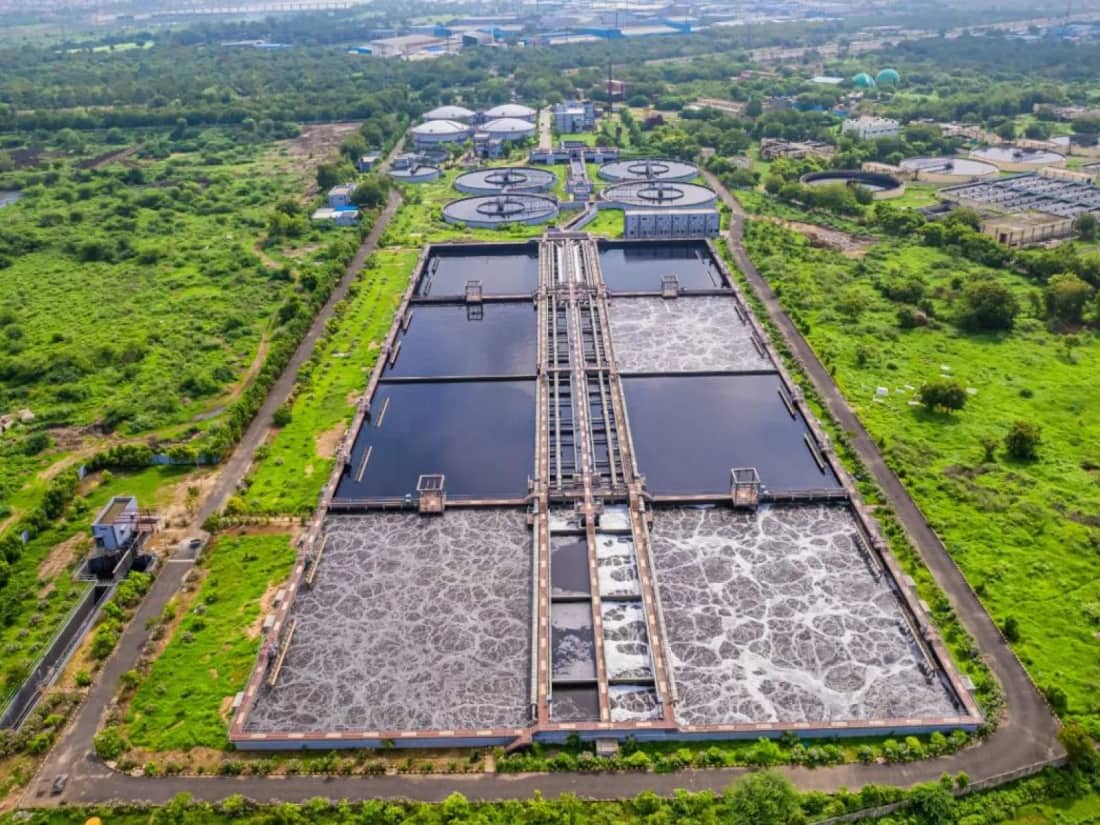 Aerial view of a large sewage treatment plant with aeration tanks and clarifiers